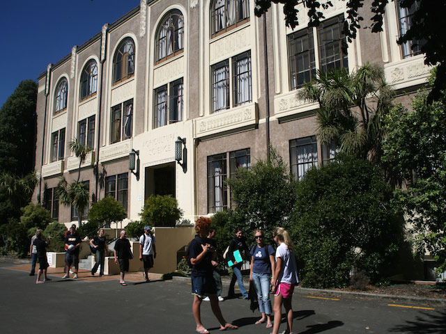 A group of students stand together outside a building on Massey University- Palmerston North campus