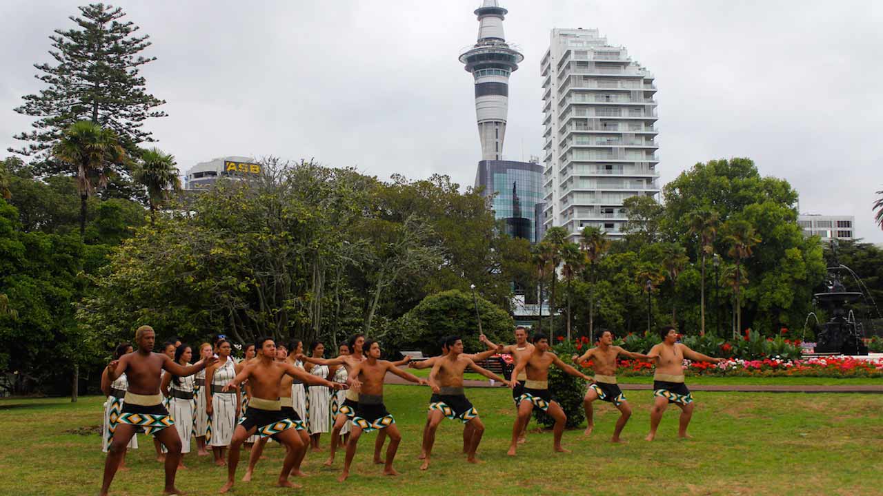 Maori men dressed in traditional attire perform a ceremony in a park in Auckland, New Zealand