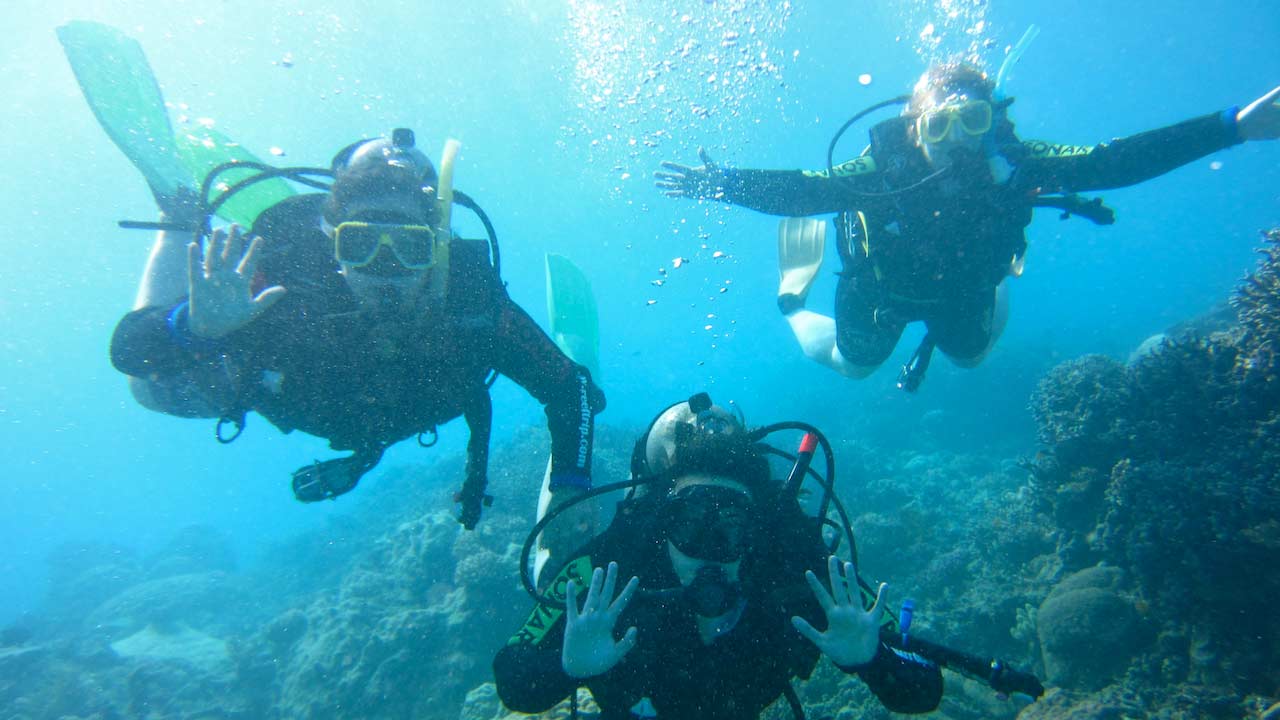 Three students posing underwater while scuba diving in the Great Barrier Reef