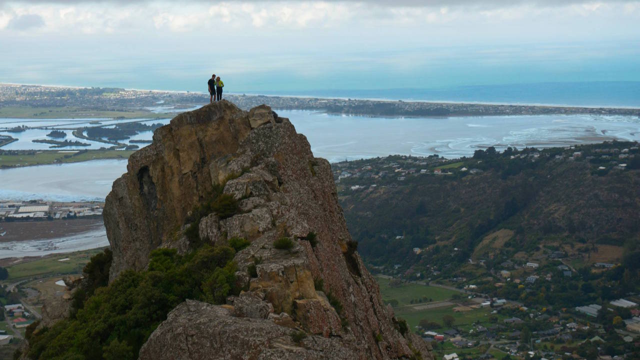 Two people stand on a mountainous peak overlooking a valley in Christchurch, New Zealand