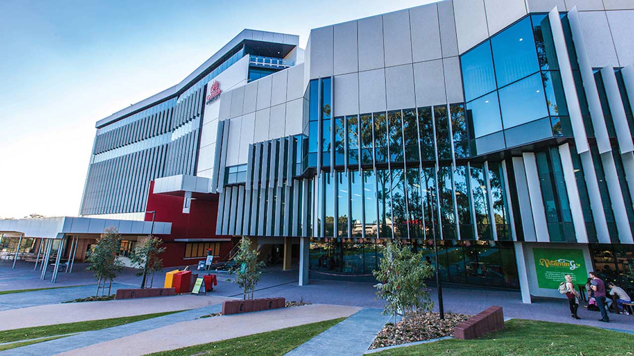 Two buildings on Griffith's Gold Coast campus with windows reflecting the blue sky and trees