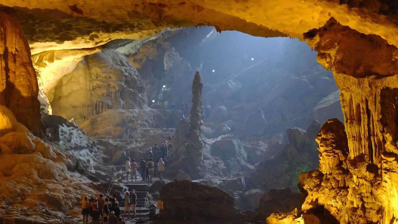 The inside of a large illuminated cave with people exploring in Vietnam