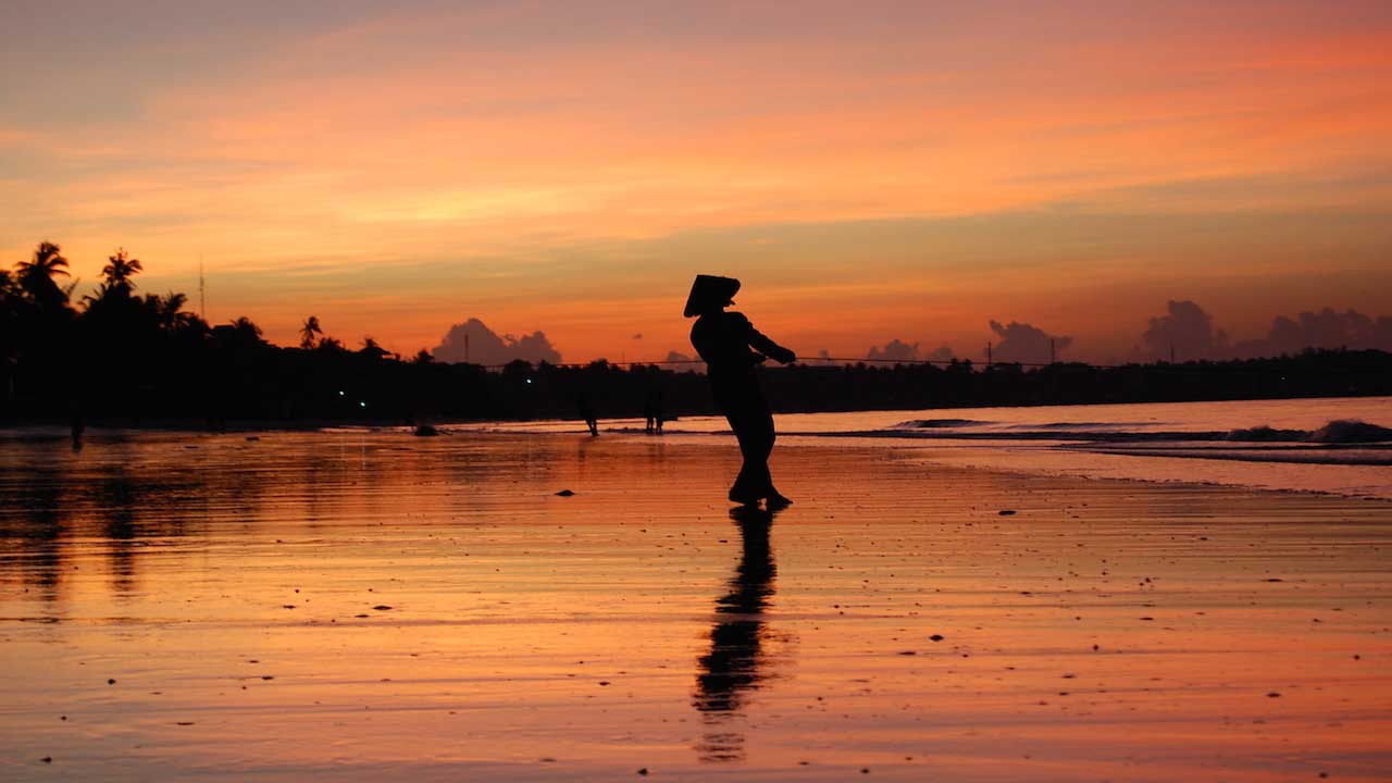 The silhouette of a fisherman casting his line into the shore at dawn in Vietnam