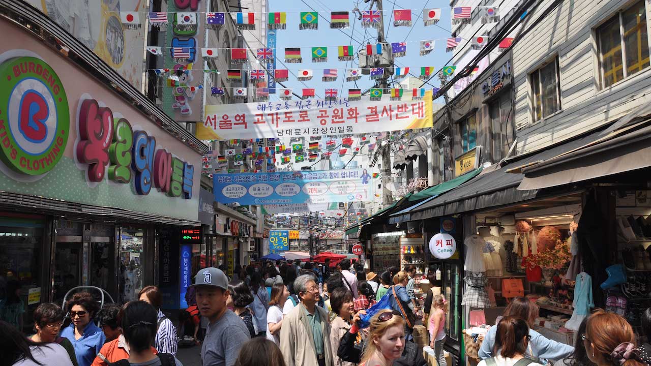 A crowded, laneway in Seoul with multinational flags strewn between buildings