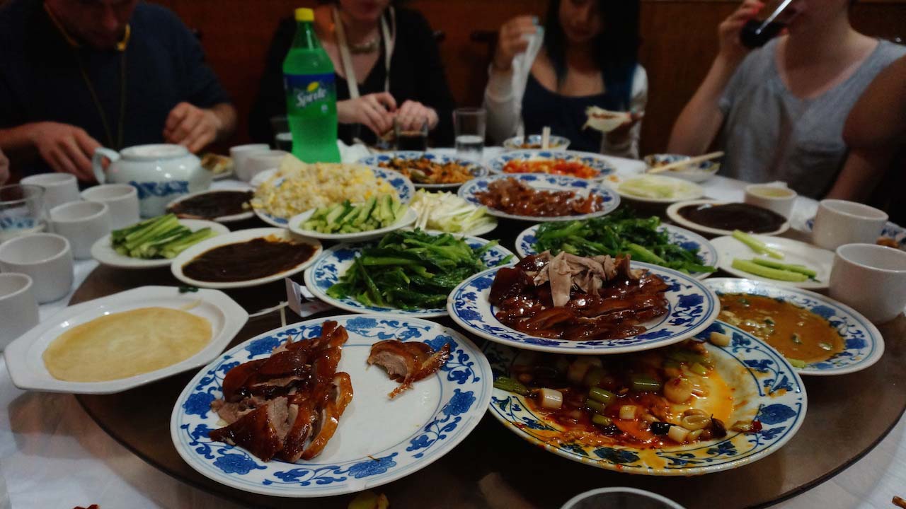 Plates of Chinese food stacked high at a table surrounded by students in Shanghai