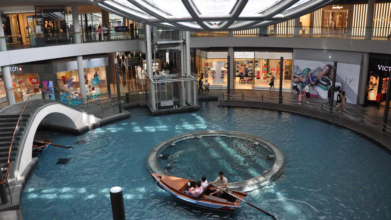 A man rows a canoe on a small body of water inside a mall in Singapore