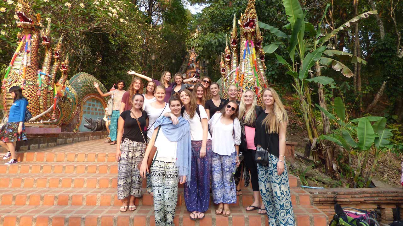 A group of women stand posing at the base of Wat Doi Suthep in Chiang Mai, Thailand