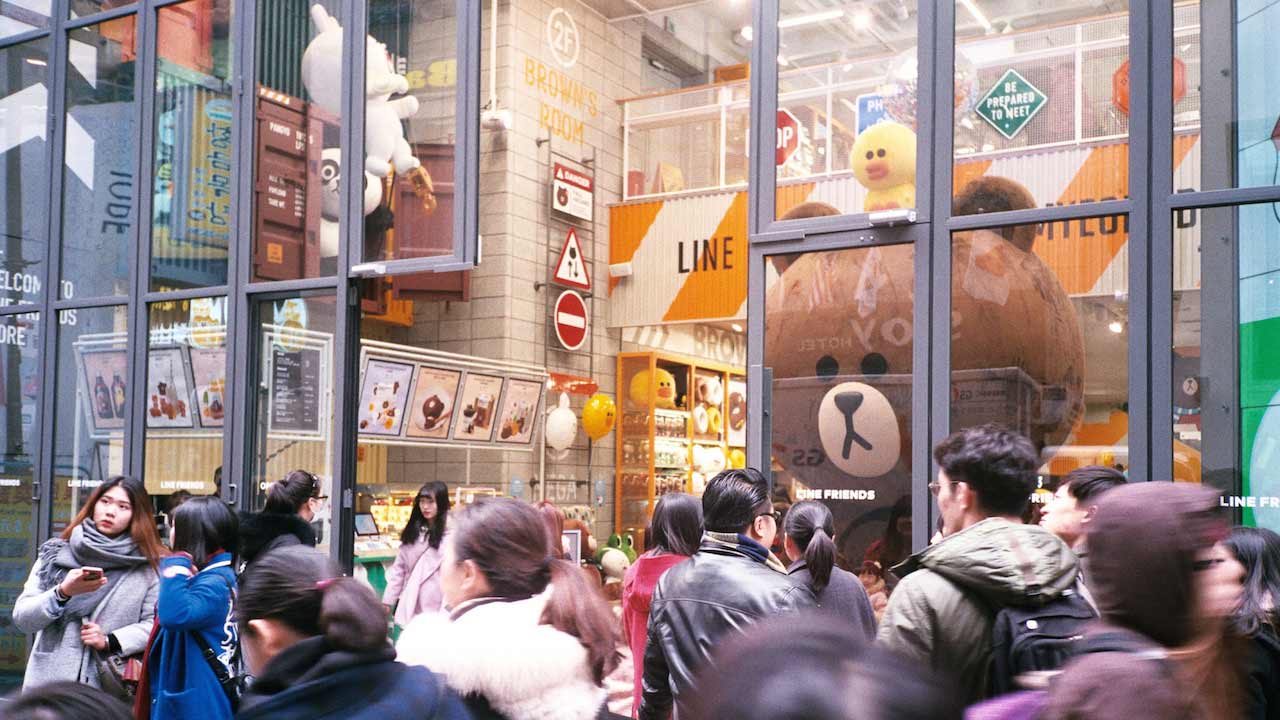 A crowded entrance to a mall with glass windows in Korea