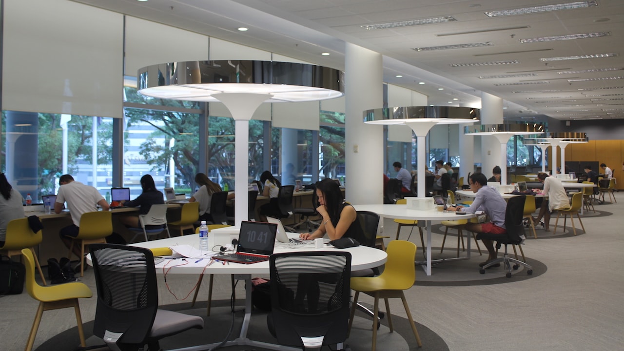 Students sit around round tables in a study room at Singapore Management University