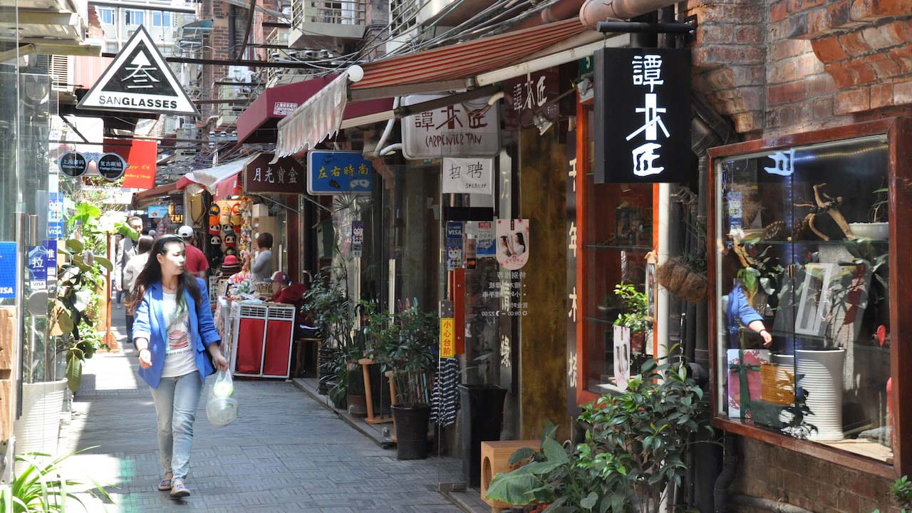 A woman walks down a laneway lined with stores and restaurants in Shanghai