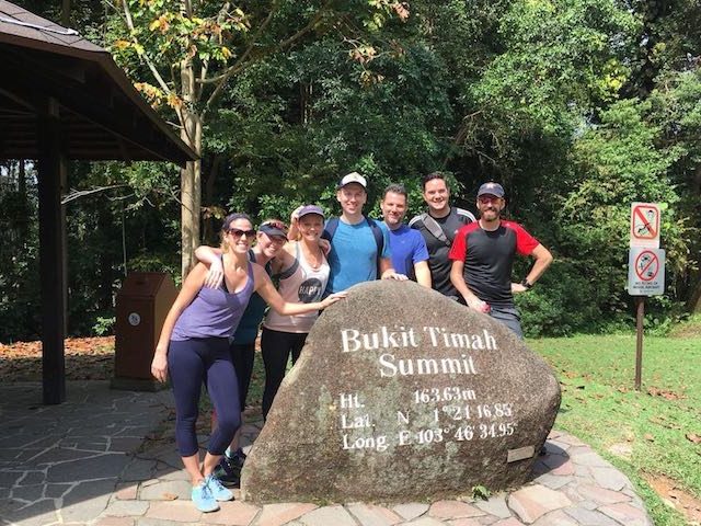 Group of people standing in front of Bukit Timah Summit sign