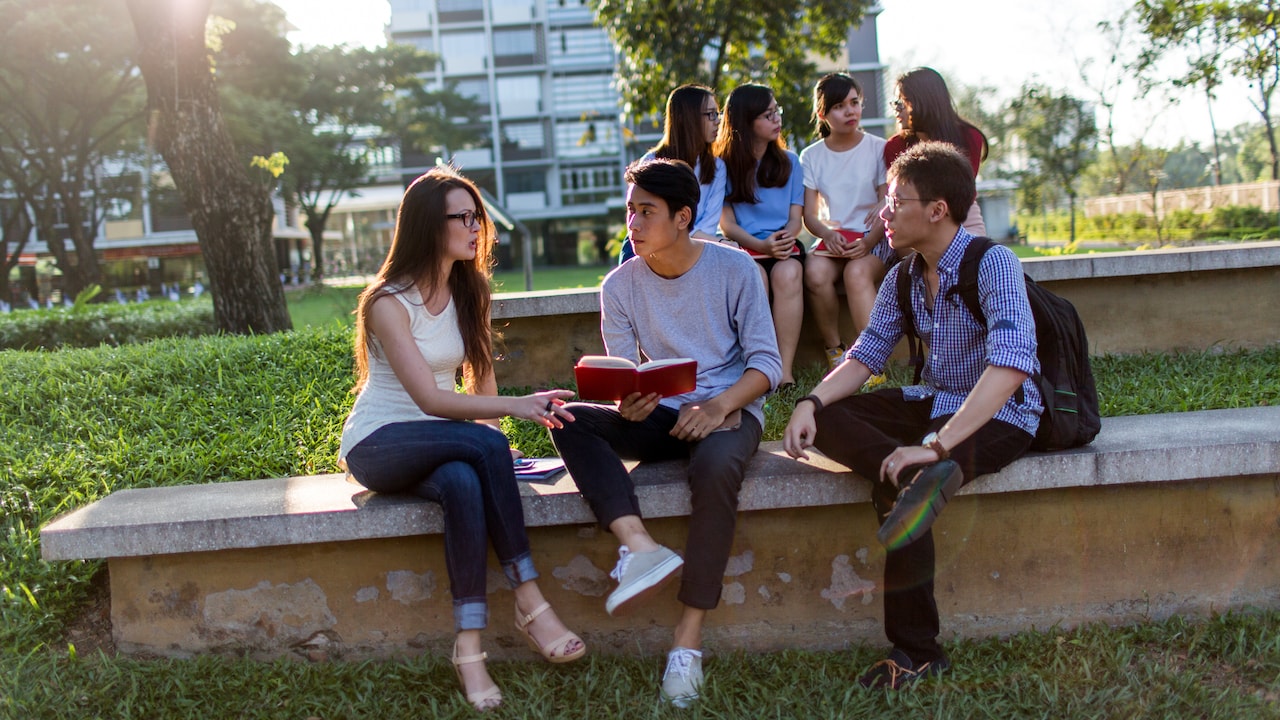 Students sitting together with an open book on campus at RMIT University Vietnam